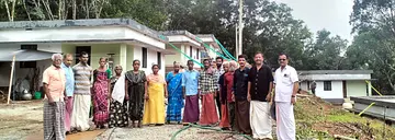 കല്ലപ്പള്ളി ബട്ടോളി പത്തുകുടിയിലെ  കുടുംബങ്ങൾ പുതിയ  വീടുകൾക്ക് മുന്നിൽ 