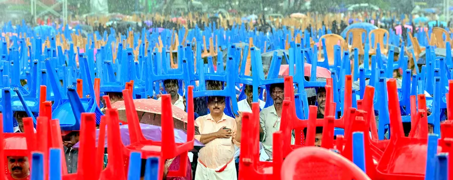 സിപിഐ എം വിപുലീകൃത ജില്ലാ കമ്മിറ്റിയുടെ ഭാഗമായി സംഘടിപ്പിച്ച പൊതുയോഗത്തിനിടെ മഴ പെയ്തപ്പോൾ കസേരകൾ തലയിൽ വച്ച് നിൽക്കുന്നവർ  /ഫോട്ടോ : സുമേഷ് കോടിയത്ത്