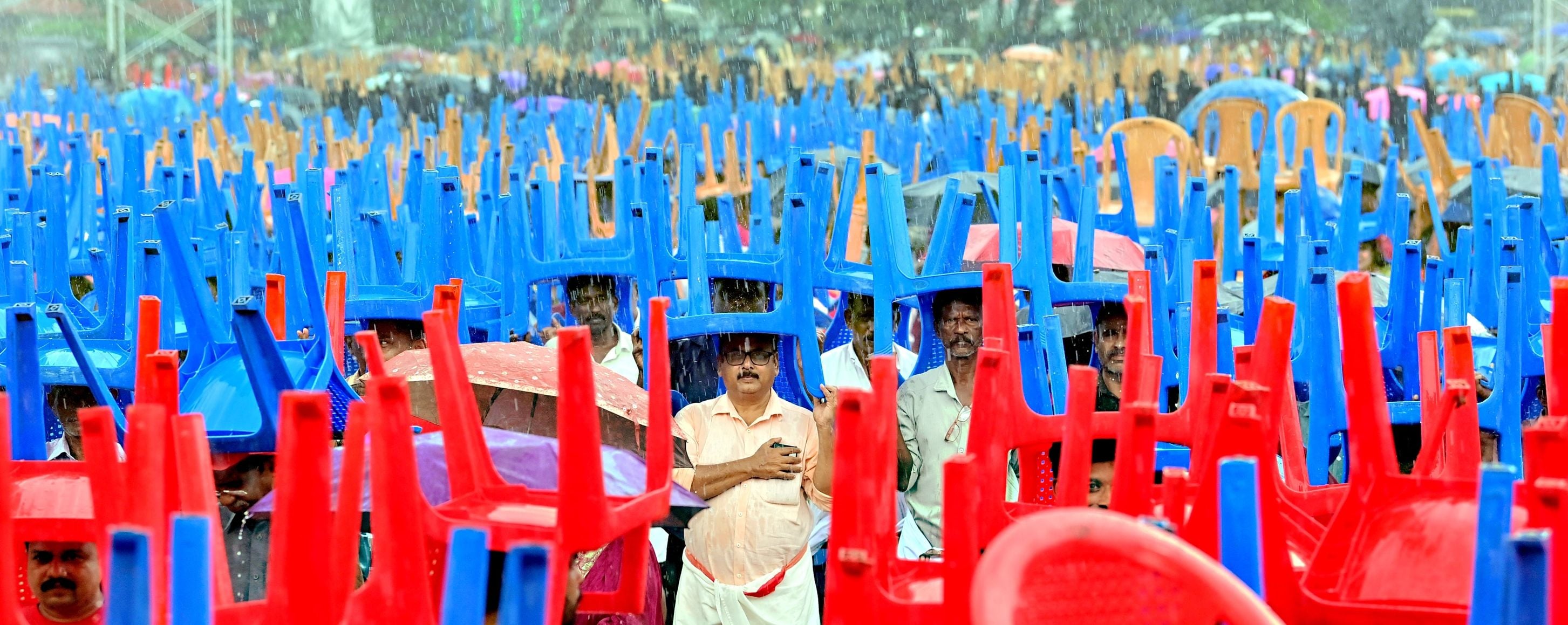 സിപിഐ എം വിപുലീകൃത ജില്ലാ കമ്മിറ്റിയുടെ ഭാഗമായി സംഘടിപ്പിച്ച പൊതുയോഗത്തിനിടെ മഴ പെയ്തപ്പോൾ കസേരകൾ തലയിൽ വച്ച് നിൽക്കുന്നവർ  /ഫോട്ടോ : സുമേഷ് കോടിയത്ത്