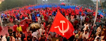 സിപിഐ എം വിപുലീകൃത ജില്ലാ കമ്മിറ്റിയുടെ ഭാഗമായി സംഘടിപ്പിച്ച പൊതുയോഗത്തിനിടെ മഴ പെയ്തപ്പോൾ കസേരകൾ തലയിൽ വച്ച് നിൽക്കുന്നവർ  