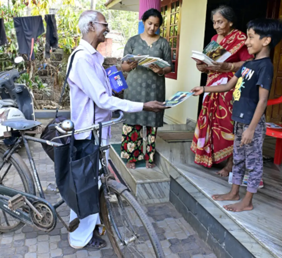 എച്ച് കെ ദാമോദരൻ സെെക്കിളിലെത്തി വീടുകളിൽ പുസ്തകം നൽകുന്നു