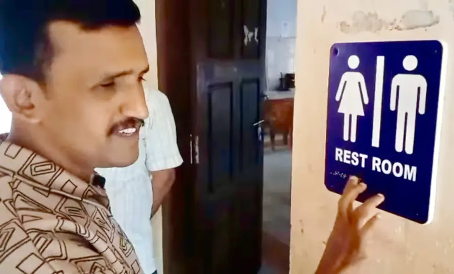 അഡൂർ ജിഎച്ച്എസ്എസ്സിൽ സ്ഥാപിച്ച ഭിന്നശേഷി സൗഹൃദ ബ്രെയിൽ ലിപി സൂചനാ ബോർഡുകൾ അധ്യാപകൻ സതീശൻ ബേവിഞ്ച പരിശോധിക്കുന്നു