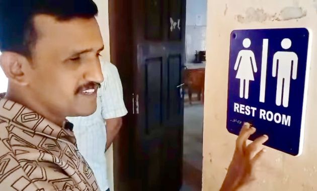 അഡൂർ ജിഎച്ച്‌എസ്‌എസ്സിൽ സ്ഥാപിച്ച ഭിന്നശേഷി സൗഹൃദ ബ്രെയിൽ ലിപി സൂചനാ ബോർഡുകൾ  അധ്യാപകൻ സതീശൻ ബേവിഞ്ച പരിശോധിക്കുന്നു