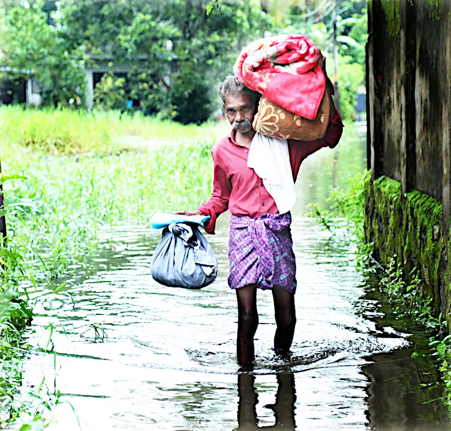 വെള്ളം കയറിയ വീട്ടിൽനിന്ന് ദുരിതാശ്വാസ ക്യാമ്പിലേക്ക് പോകുന്ന ഗൃഹനാഥൻ