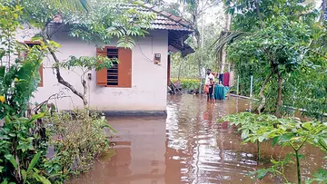 വെളളം കയറിയ വീടിന് പുറത്ത് നിൽക്കുന്നവർ