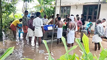 ക്യാമ്പിലേക്ക് പോകുന്നതിനിടെ തോട്ടിൽവീണ് മരിച്ച ഓമനയുടെ മൃതദേഹം  താൽക്കാലിക സംവിധാനമൊരുക്കി സംസ്‌കരിക്കുന്നു