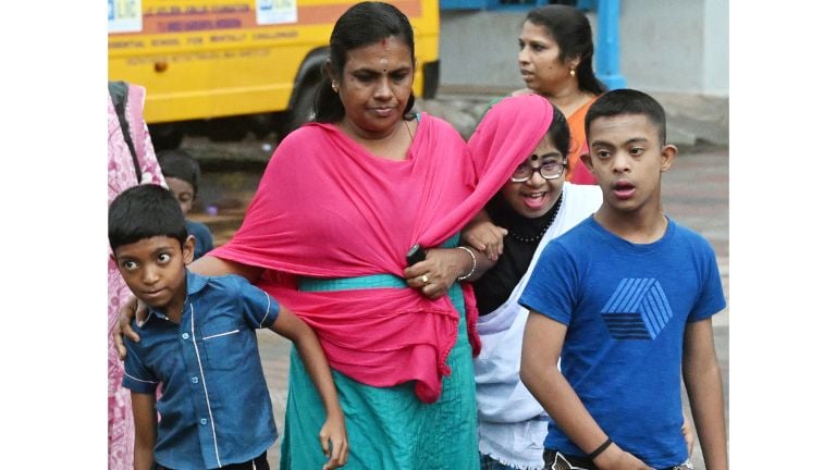 ചാറ്റൽ മഴയിൽ അധ്യാപികയുടെ ഷാൾ മറയാക്കി  മത്സരത്തിൽ പങ്കെടുക്കാൻ പോകുന്ന  കുട്ടി