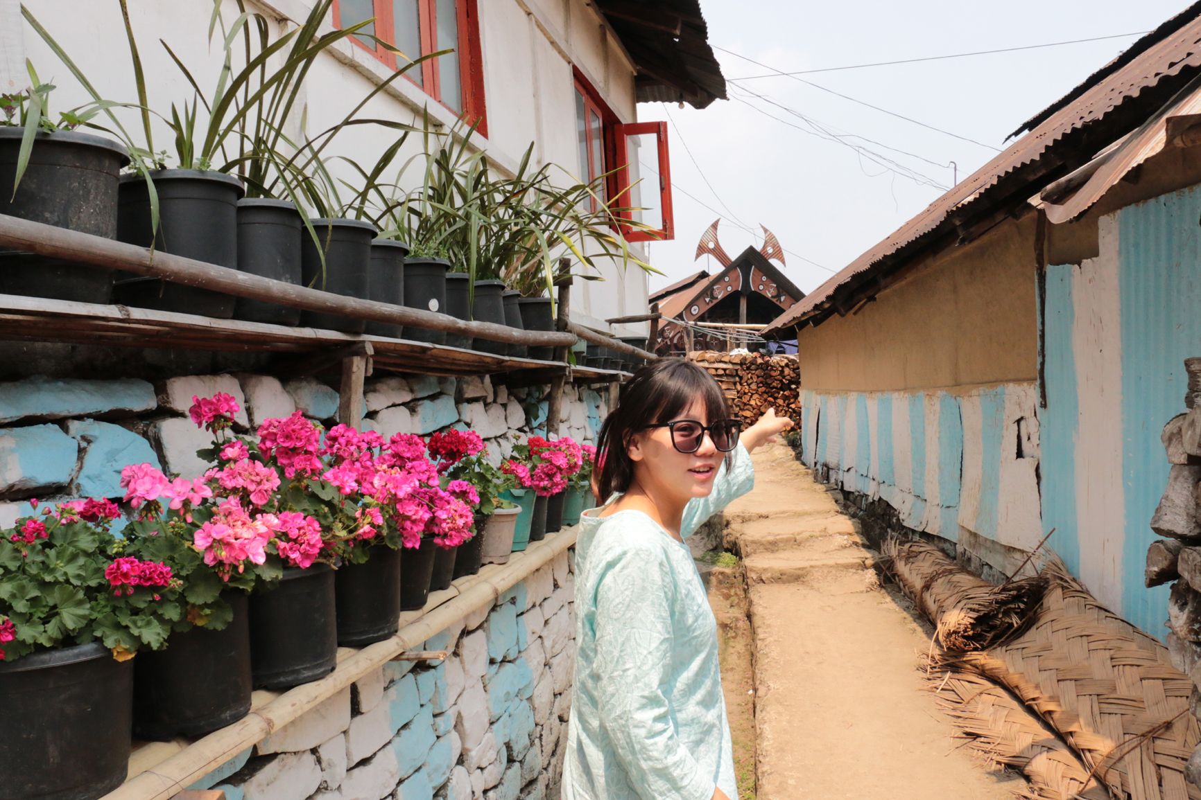 കിഗ്വേമാ ഗ്രാമത്തിലെ നീലയും വെള്ളയും ചായമടിച്ച കൽമതിലിനടുത്ത്‌ ഗൈഡ്‌ ആനോ