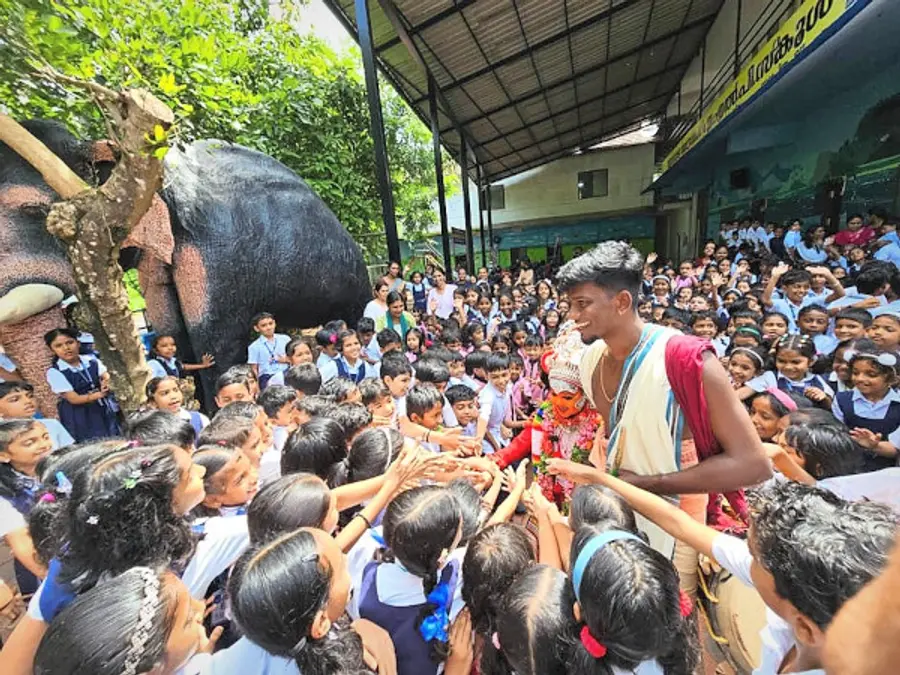 മോറാഴ സൗത്ത് എഎൽപി സ്കൂളിലെത്തിയ ആടിവേടനും സഹായി അഖിലേഷ് പണിക്കറിനുമൊപ്പം കുട്ടികൾ