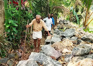 പാടശേഖര ബണ്ടിൽ നിർമാണത്തിനായി ഇറക്കിയ കല്ലുകൾക്കിടയിലൂടെ നടക്കുന്ന പ്രദേശവാസികൾ