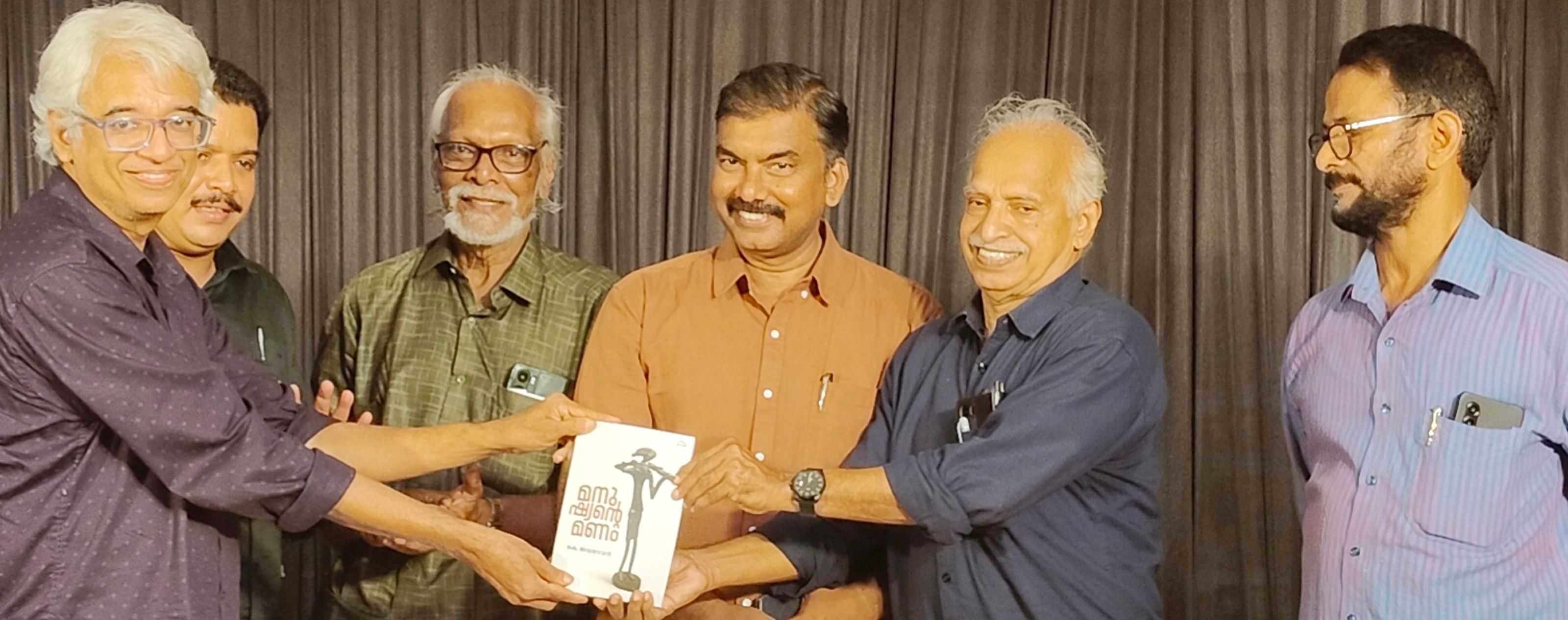 കെ ജയദേവൻ രചിച്ച ‘മനുഷ്യന്റെ മണം' പുസ്തകം സാഹിത്യകാരൻ  കെ സി നാരായണൻ കവി പി രാമന് നൽകി പ്രകാശിപ്പിക്കുന്നു 