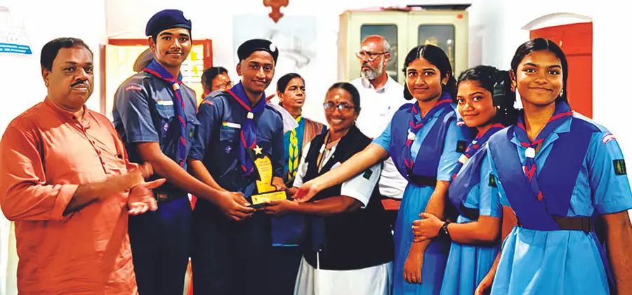Scouts and Guides students of Kattanam Pope Pius Higher Secondary School, who won the first position in the Scarf Pattern Competition organized by Bharat Scouts and Guides District Association, receive the trophy from DTC B Renuka.