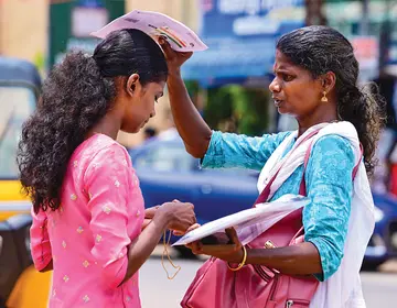 ആലപ്പുഴ എസ്ഡിവി ഗേൾസ് ഹൈസ്-കൂളിൽ നീറ്റ് പരീക്ഷയ്‌ക്കെത്തിയ വിദ്യാർഥിനി  മാല അഴിച്ചുമാറ്റുമ്പോൾ കെെയിലെ സർട്ടിഫിക്കറ്റ് കൊണ്ട് തണലൊരുക്കുന്ന അമ്മ