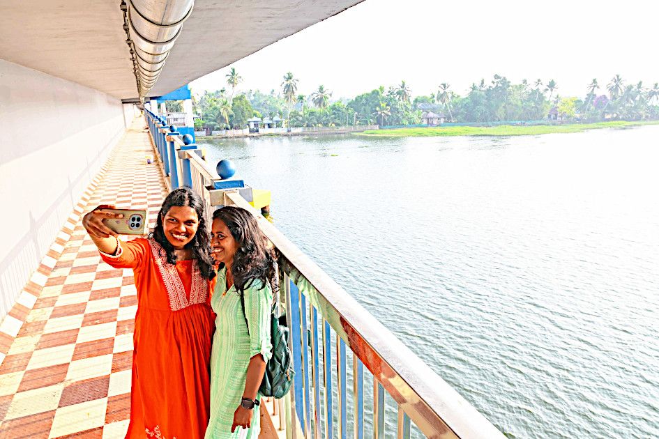 പടഹാരം പാലത്തിലെ നടപ്പാതയിൽനിന്ന് കുട്ടനാടിന്റെ സൗന്ദര്യം ആസ്വദിച്ച്  പൂക്കൈതയാർ പശ്ചാത്തലമാക്കി   സെൽഫിയെടുക്കുന്നവർ 