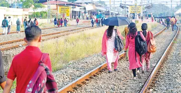 Passengers walk to the platform along the tracks, avoiding the railway station road due to ongoing construction work.