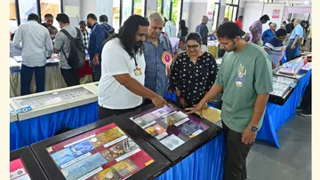 അഭിജിത്തും അച്ഛൻ സന്തോഷും പ്രദർശനം കാണാനെത്തിയവർക്ക്  നാണയങ്ങളെക്കുറിച്ച് വിശദീകരിക്കുന്നു 