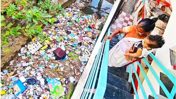 തന്റെ വീടിന്റെ അരികിലൂടെ ഒഴുകുന്ന ആമയിഴഞ്ചാൻ തോട്ടിൽ അടിഞ്ഞുകൂടിയ ദുർഗന്ധം വമിക്കുന്ന മാലിന്യം നോക്കിനിൽക്കുന്ന ലീല                                                                                                                                                                                                                                                                     