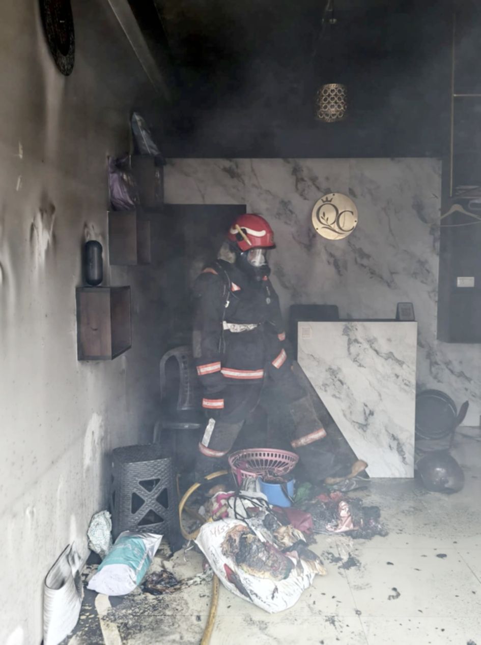ടെയ്ലറിങ് കടയിലെ തീയണയ്ക്കുന്ന  അഗ്നിരക്ഷാസേനയുടെ ഉദ്യോഗസ്ഥൻ