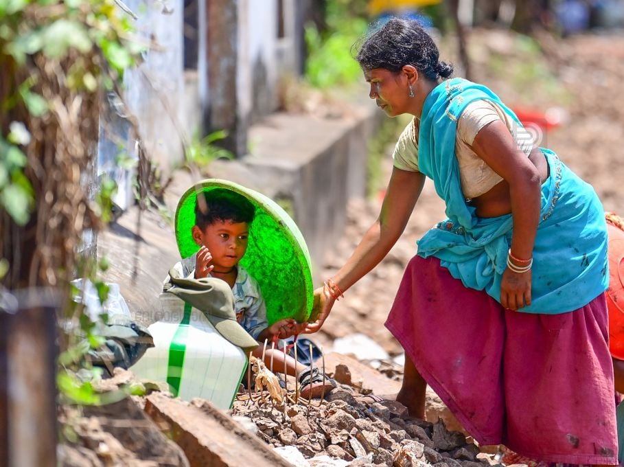 റെയിൽവേയുടെ പണിക്കായി എത്തിയവർ തന്റെ കുട്ടിയെ കനത്ത വെയിലിൽ നിന്ന് സംരക്ഷിക്കുന്നതിനായി ബക്കറ്റ് അടപ്പ് വച്ചു തല മറയ്ക്കുന്നു കൊല്ലത്തു  നിന്നുള്ള കാഴ്ച                                   ഫോട്ടോ: എം എസ് ശ്രീധർലാൽ 