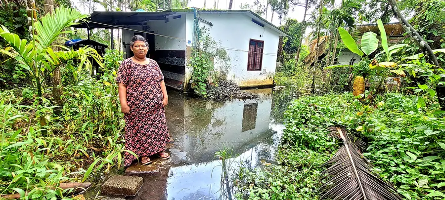 വെള്ളം കെട്ടി നിൽക്കുന്ന വീടിന് മുന്നിൽ പ്രിയ മുരുകേശൻ